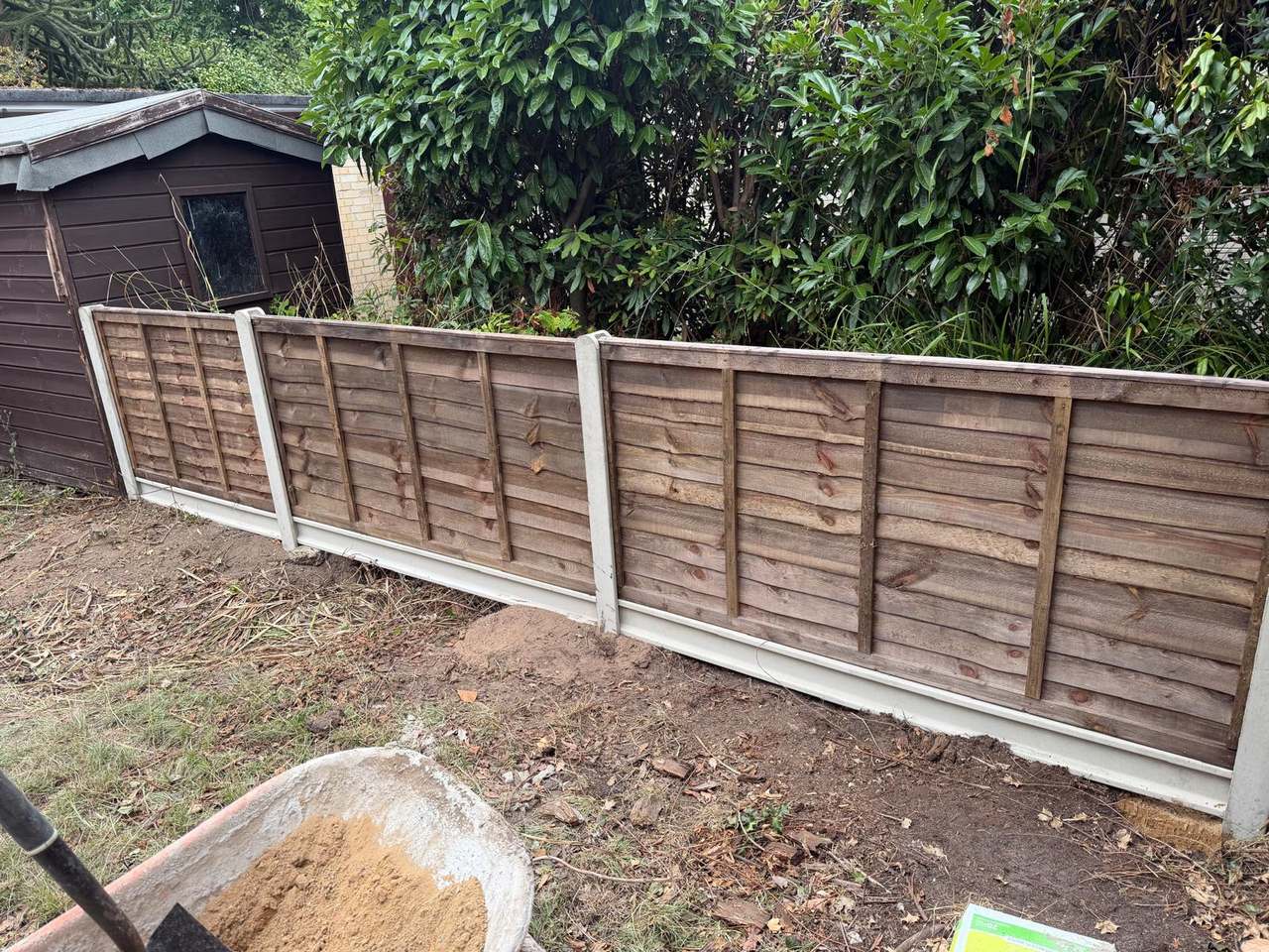 Closeboard fence panels and concrete gravel boards set along a boundary beside a timber shed