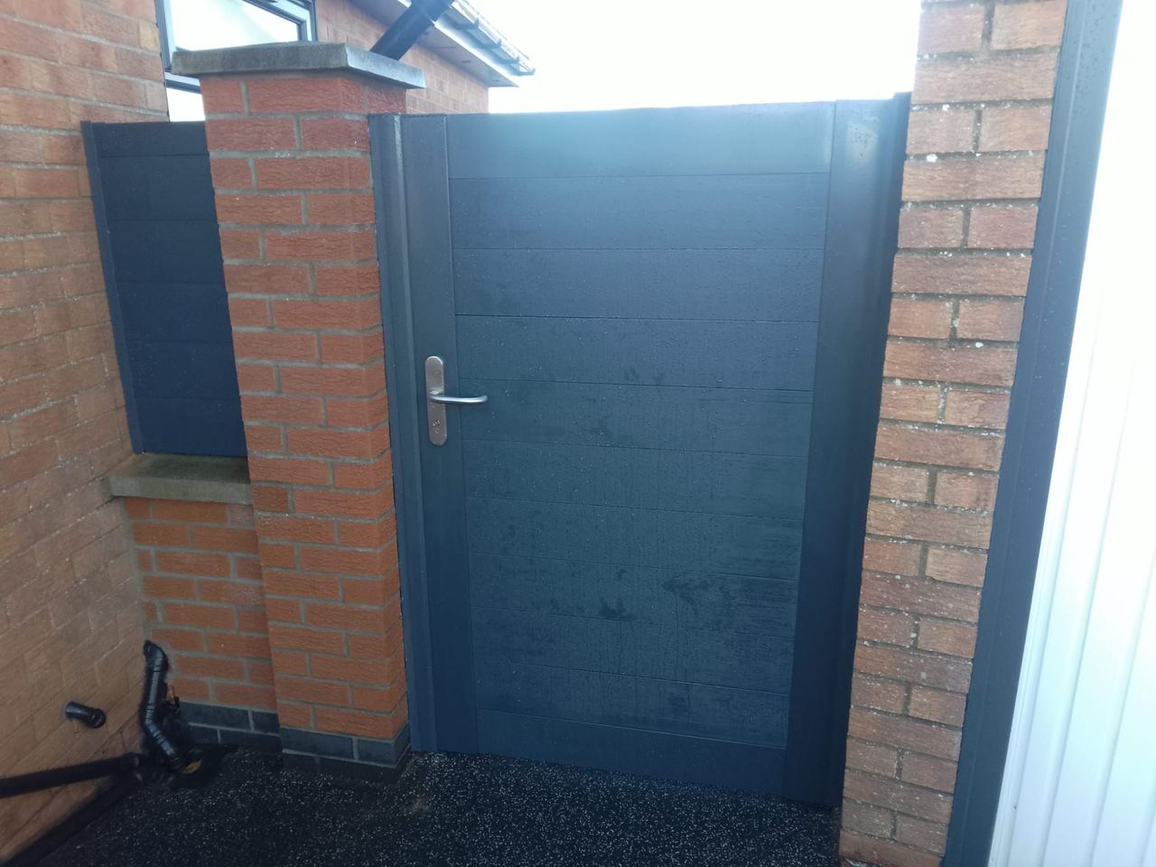 Anthracite grey side gate between brick walls