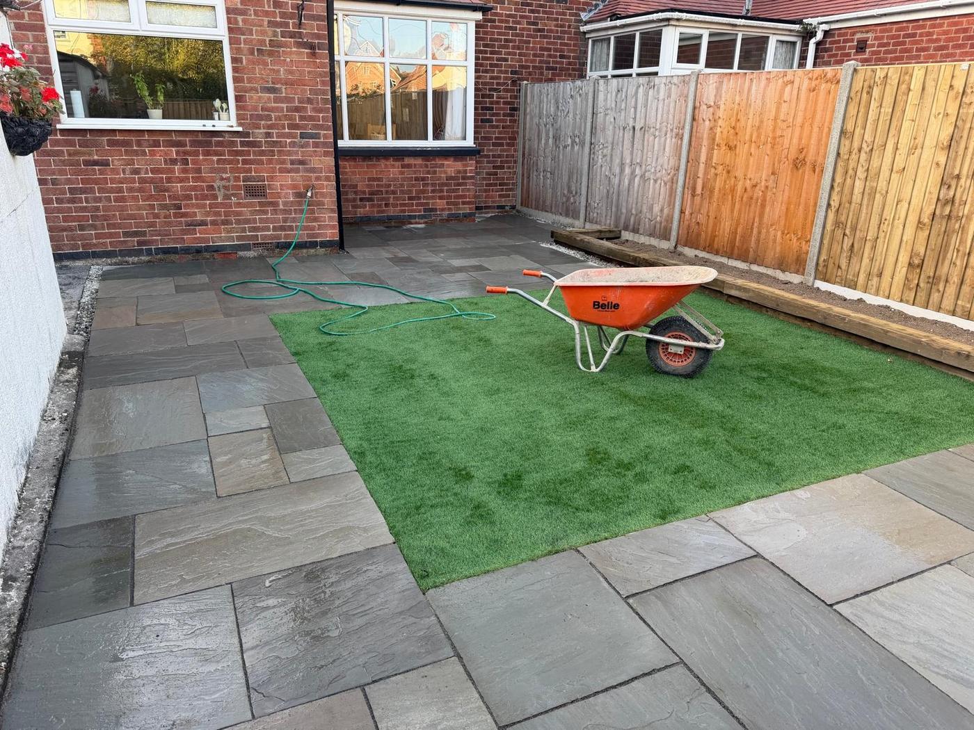 Grey paving and artificial lawn seen from the side of the house