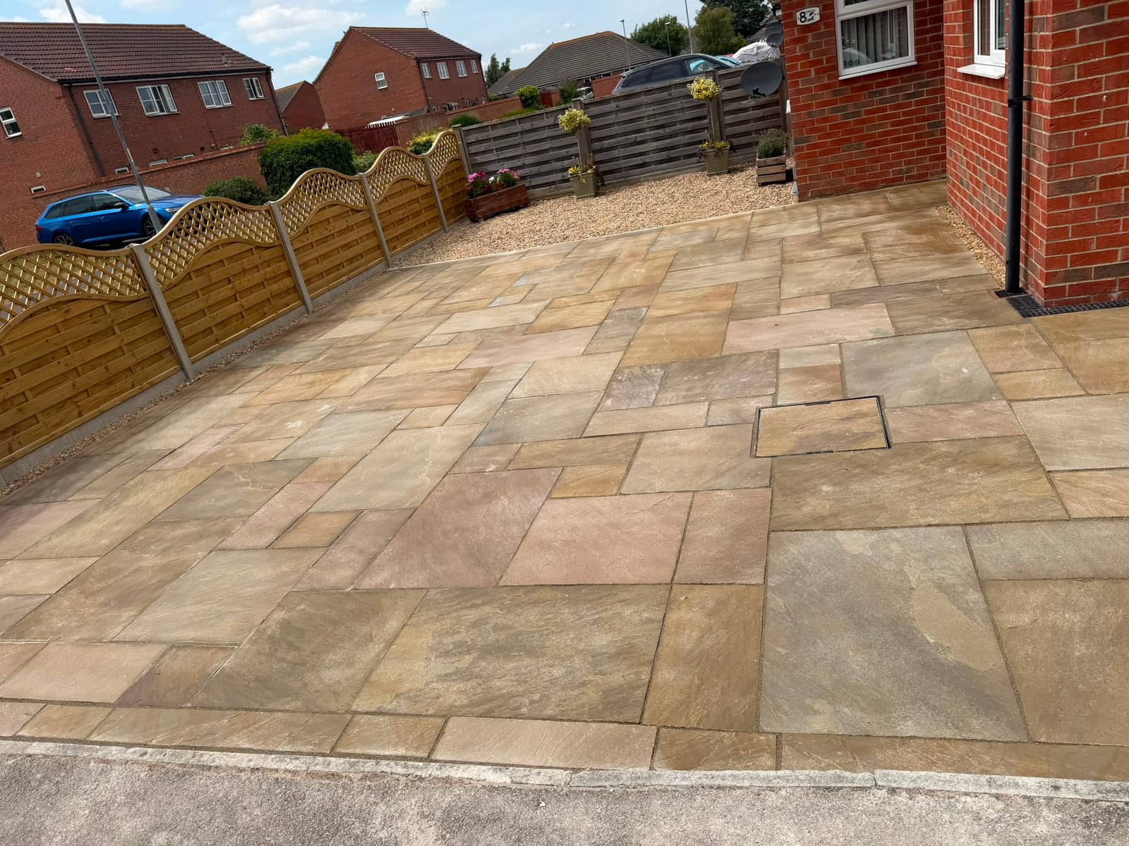 Finished sandstone patio seen from the house, fencing and planters along the edge