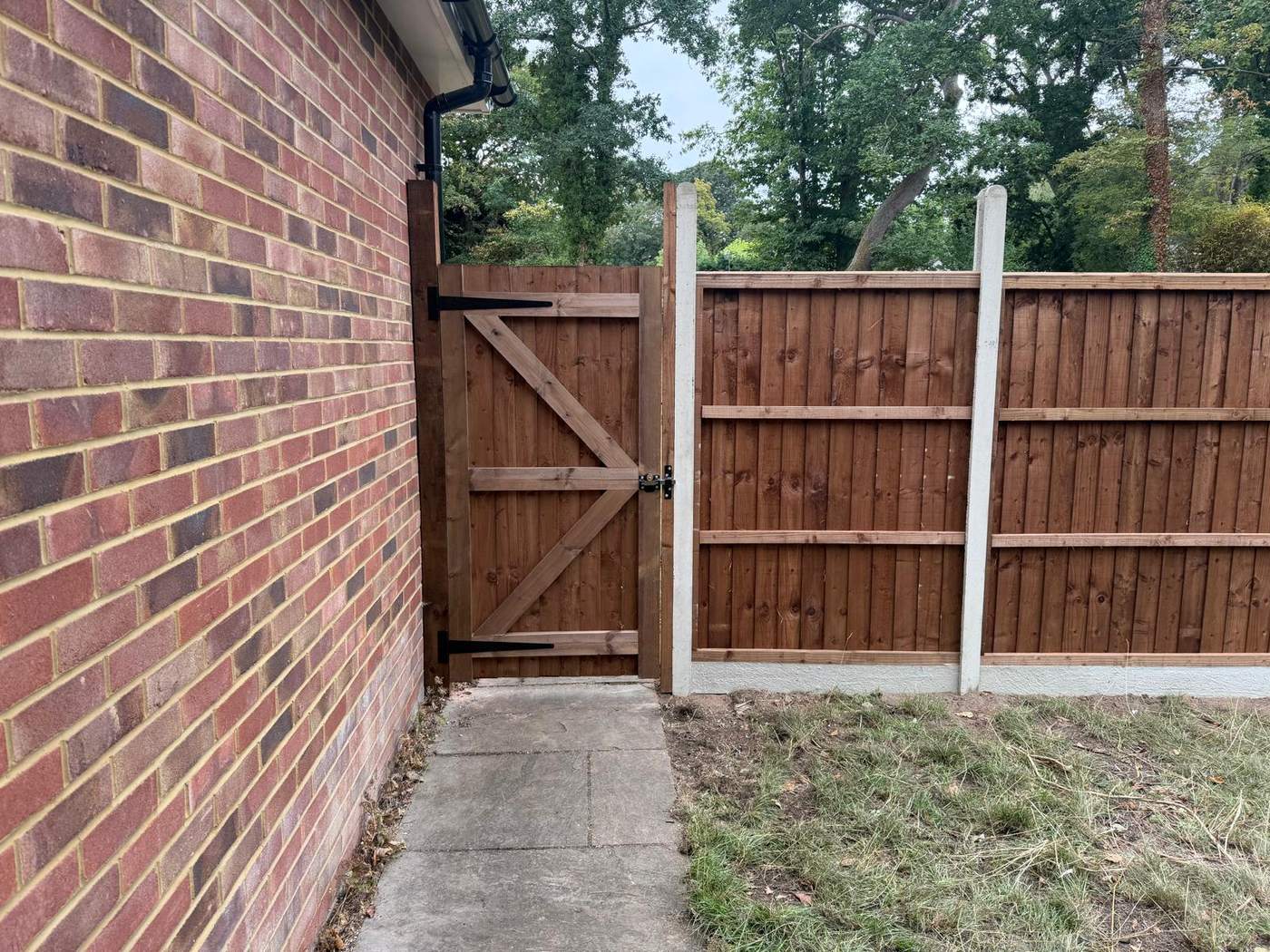 Braced timber side gate hung between the house wall and a new closeboard fence