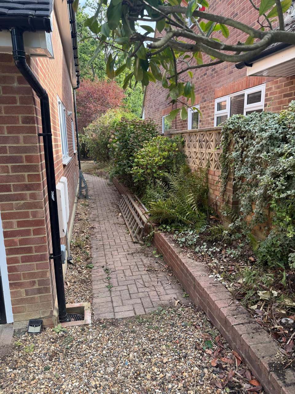 Block paved side path running between the house wall and a raised planted border